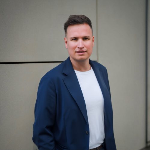 Mann im blauen Sakko vor heller Wand